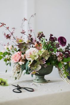 a vase filled with lots of flowers sitting on top of a table next to scissors