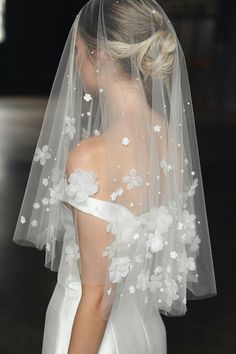 the back of a bride's veil with flowers and leaves on it, as seen from behind