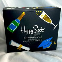 a black box with congratulations socks and graduation caps on it that says happy socks next to a glass of champagne