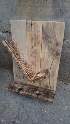 a piece of wood sitting on top of a cement floor next to a wall with two pieces of wood sticking out of it