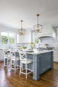 a large kitchen with white cabinets and blue island