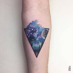 a small triangle tattoo on the right thigh with an image of planets and stars in it