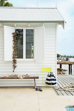 a white house with a yellow chair sitting in front of it and a blue and white bag on the ground