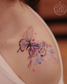 a woman's breast with a butterfly tattoo on her left shoulder and purple flowers in the middle