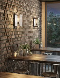 a brick wall with two lights on it and some tables in front of it next to a window