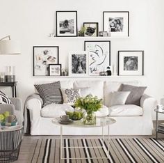 a living room filled with white furniture and pictures on the wall above it's coffee table