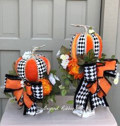 two pumpkins decorated with black and white checkered bows on top of a table