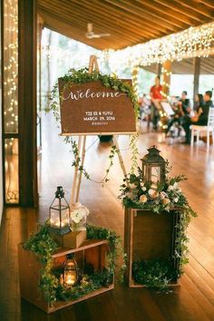 the welcome sign is surrounded by greenery and lanterns for an outdoor wedding reception at night