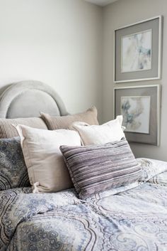 a bed with pillows and pictures on the wall