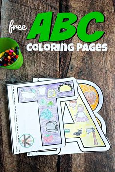 the abc coloring pages are next to some crayons and pencils on a wooden table