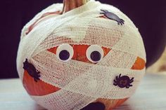 a decorated pumpkin with googly eyes and a bandaged face