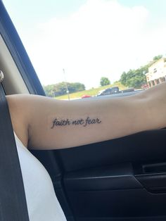 a woman's arm with the words faith not fear tattooed on it