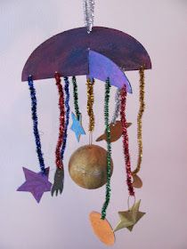 a wind chime with beads and stars hanging from it's sides, on a white wall