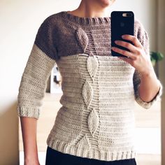 a woman is taking a selfie with her cell phone while wearing a knitted sweater