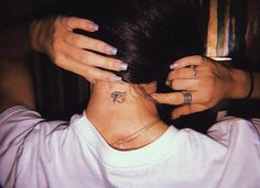 a woman has a small tattoo on her neck and behind her head is a white t - shirt