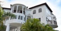 a large white house surrounded by palm trees