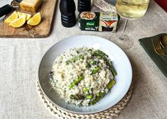 a bowl of rice and asparagus on a table next to some wine glasses