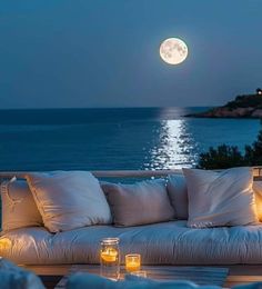 an outdoor couch with candles on it and the moon in the sky