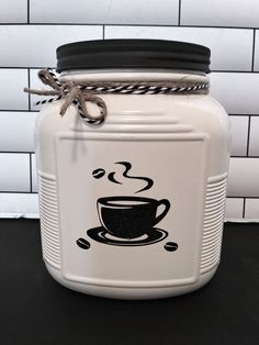 a white jar with a black coffee cup on the lid and rope wrapped around it