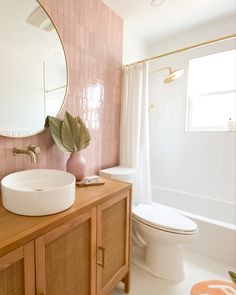 a bathroom with pink tile and wooden vanity, mirror, toilet and bathtub in it