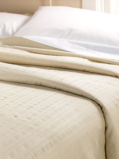 an unmade bed with white sheets and pillows