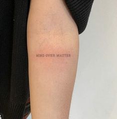 a woman's arm with the words mind over matter written on her left side