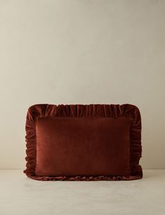 a red pillow with ruffled edges on a white surface