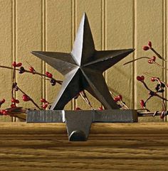 a metal star sitting on top of a wooden table next to a plant with red berries