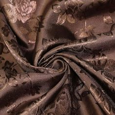 a close up view of a brown and black floral print satin fabric with flowers on it