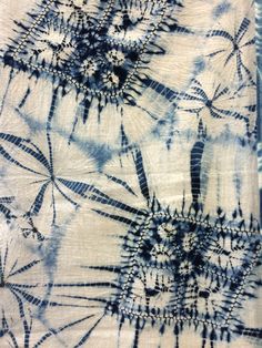 blue and white tie - dyed fabric with small flowers on the bottom, as well as other designs