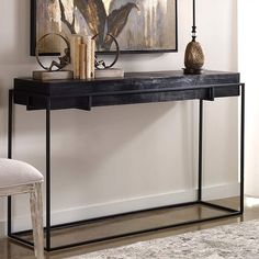 a console table with two candles on top and a painting above it in a living room