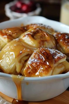 a bowl filled with cinnamon rolls covered in syrup