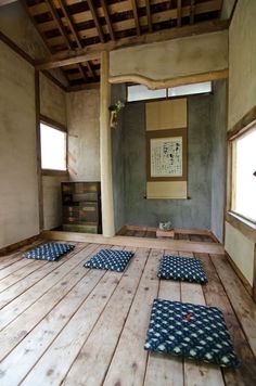 an empty room with wooden flooring and blue mats on the floor in front of windows