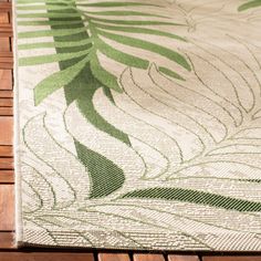 a green and white rug sitting on top of a wooden floor next to a plant