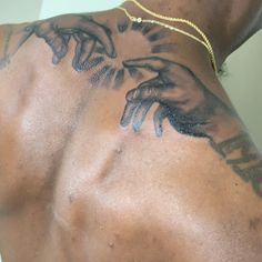 the back of a man's chest with tattoos on his arm and hand holding something