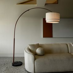 a living room with a couch, lamp and mirror on the wall next to it