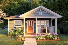 a small house with flowers in the front yard and landscaping around it's porch