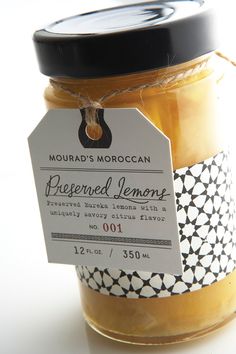 a jar of preserves sitting on top of a white table next to a black and white tag