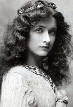 an old black and white photo of a woman with long hair wearing a tiara