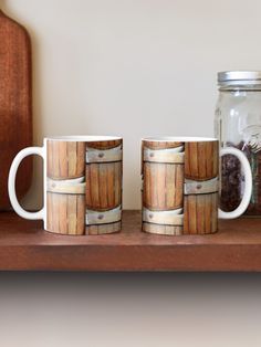 two coffee mugs sitting on top of a wooden shelf next to a mason jar