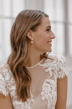 a woman with long hair wearing a white dress and smiling at something in front of her