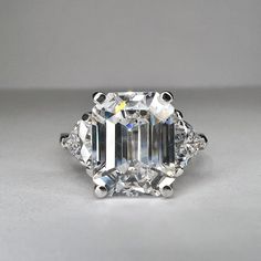 an emerald - cut diamond ring with three diamonds on the sides and four prongs