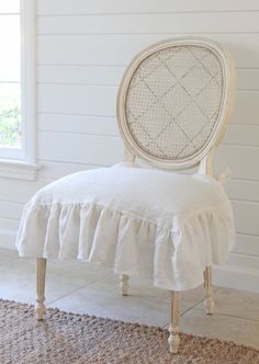 a white chair sitting on top of a rug next to a window