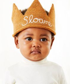 a baby wearing a knit crown with the word slone on it