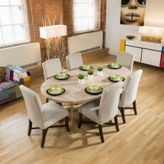 a dining room table with white chairs and plates on it in front of a couch