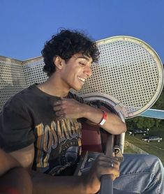 a young man sitting in the driver's seat of a car with his hand on the steering wheel