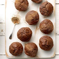 several chocolate muffins on a white tray with a spoon