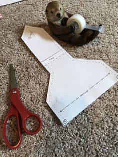 a pair of scissors next to a cut out piece of paper on the floor with an animal in it