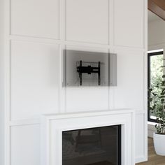 there is a television mounted on the wall above the fireplace in this living room with white walls