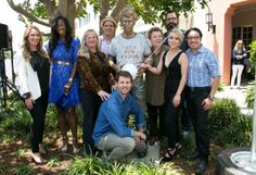 a group of people standing next to each other in front of a tree and building